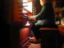 A man is seated at an organ manual, playing.