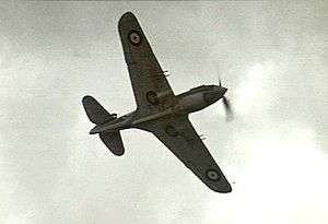 Underside of single-engined monoplane in flight, with twin machine guns on each wing