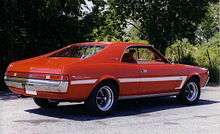 Shows the rear right of a 1969 AMC Javelin SST finished in red with white bodyside C stripe