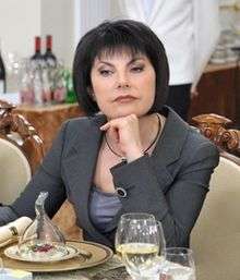A woman with black hair, Tatyana Mitkova, sitting at a table