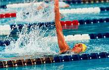 A woman swims the backstroke between two lanes in a swimming pool.