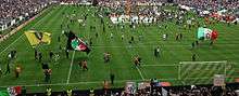 A crowd of Juventus Ultras in Curva Scirea (South) celebrates the 2012–13 scudetto with a pitch invasion.