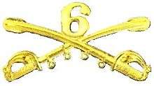 A computer generated reproduction of the insignia of the Union Army 6th Regiment cavalry branch. The insignia is displayed in gold and consists of two sheafed swords crossing over each other at a 45 degree angle pointing upwards with a Roman numeral 6