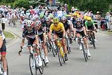 A group of cyclists, with one wearing a yellow jersey.