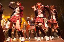 Girls in short skirts singing onstage