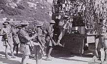 Soldiers in tropical uniforms climb on to a truck