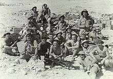 Australian soldiers sitting amongst desert rubble
