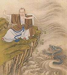 Painting of a thin balding man with a mustache and his hair tied behind his head, wearing a loose brown robe over a white robe tied by a blue sash. He is sitting on a cliff covered with thin green grass and a few white flowers. The thumb and index of his extended right hand are held together and the three other fingers are raised. His left arm is folded toward his chest and he is holding a long and thin object. Under the cliff is a metallic-blue dragon with three claws on each paw who is emerging from stylized waves.