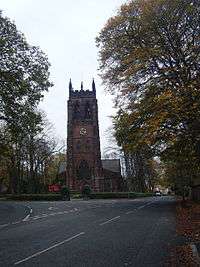 A tower seen from a distance, with a clock face and pinnacles