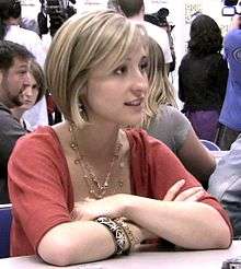 Young, blonde woman with arms folded at a table