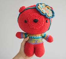 Amigurumi bear. Example of a big size Amigurumi. Self made. Color used are red, blue and green. It has a flower decoration in the head.