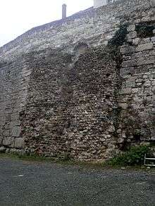 Vue d'un massif de maçonnerie plaqué contre un mur en moyen appareil.