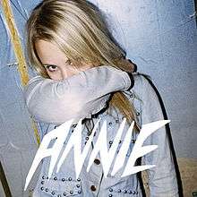The cover of Anniemal featuring the word Annie at the bottom and showing Annie, a twentysomething blonde woman, with her arm covering her mouth