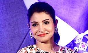 Anushka Sharma is wearing a printed top and smiling away from the camera