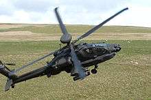 Photograph of an AgustaWestland Apache of 656 Squadron flying low over grassy land