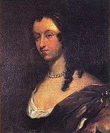Dark portrait of woman with should length curly black hair and pearl necklace