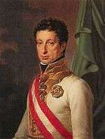 Painting shows a sober-looking curly-haired man in a white military uniform with a red and white sash and a gold collar.