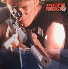 Assault on Precinct 13 soundtrack cover, featuring a still from early in the film in which one of the gang lords is sitting in the back seat of a car looking though the scope of a assault rifle.