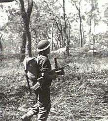 A soldier advances through the bush with a submachine-gun during training