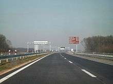 A view of motorway and a traffic sign indicating distances to tourist destinations