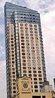 BKLYN AIR, a high-rise building with curved steel and glass corners, viewed on the right from a distance along an avenue