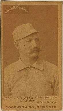 A baseball player is shown sitting, facing slightly right of the camera.