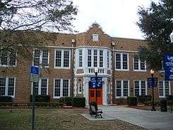  an old two story brick building with an orange doors and blue banners