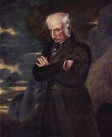 Three-quarter portrait of elderly man with a fringe of white hair around his head, looking down introspectively with his arms crossed. He is wearing a brown suit and is set against a brown, blue, and purple background that is reminiscent of rocks and clouds.