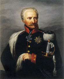 Painting of a white-haired, mustachioed man with a stern expression. He wears a dark blue military uniform with a large iron cross at his neck.