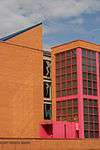 An orange brick building with pink window frames and a blue roof