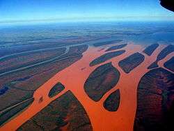Aerial photograph of a forked river that has turned red due to red soil runoff.