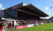 One of the stands of the Bootham Crescent association football ground, with supporters sitting down and a grass field below