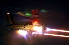 Photograph of an AgustaWestland Apache firing CRV7 rockets at night.