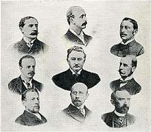 A late 19th-century lithograph showing the heads and shoulders of nine gentlemen in three rows. The man in the centre appears to have been deliberately made more prominent than the others, appearing larger and more strongly drawn.