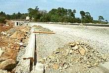 An incomplete road surface leading into trees