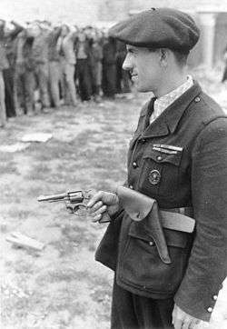 Man in uniform, wearing a beret and holding a revolver