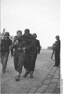 two British soldiers one wounded being escorted by three armed Germans