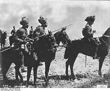 Three Indian horsemen in the foreground, the man on the left carries a lance a sergeant is in the middle and an officer on the right. In the background can be seen three further cavalrymen