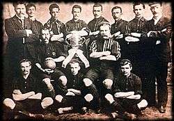 Old team photo, with players around a trophy