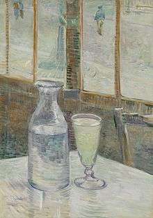 A table in a cafe with a bottle half filled with a clear liquid and a filled drinking glass of clear liquid