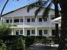 A white, two-story building surrounded by trees