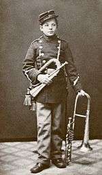 photograph of young Nielsen in band parade uniform with two brass instruments