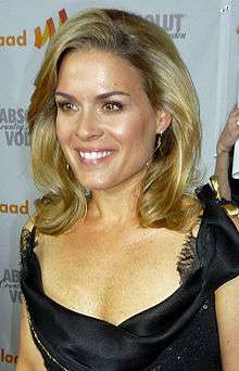  Head and shoulders color photograph a smiling young woman with shoulder-length blond hair wearing a low-cut black dress