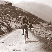 A man on a bicycle, riding on a mountain road.