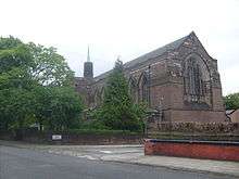 A Gothic Revival church in red brick with a small tower and thin spire
