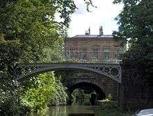 Cast iron bridges over water, with a yellow stone building under which passes the canal tunnel