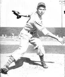 A black-and-white image of a man in a white baseball uniform following through after throwing a ball