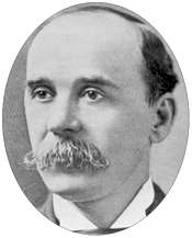 Head of a white man with a receding hairline and a bushy mustache hanging over his mouth.