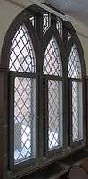 A triptychal window overlaid with diagonal grid paneling and stone tracery