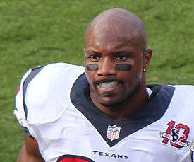  An African-American football player without a helmet on. Mouthgear and eyeblack are visible